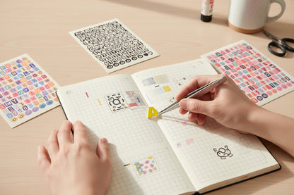 Four sheets of alphabet and number stickers on a beige surface