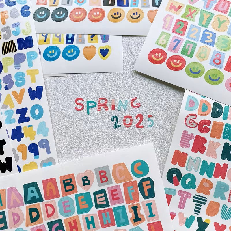 Colorful alphabet and number stickers with 'Spring 2025' text on a light gray background